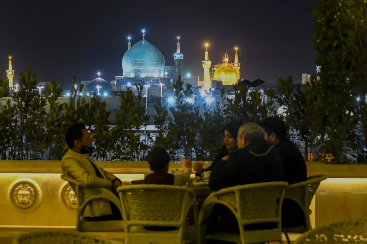 تصویر شبانه یک خانواده 4 نفره در روف‌گاردن هتل رز درویشی مشهد با نمای حرم امام رضا (ع) در مقابلشان