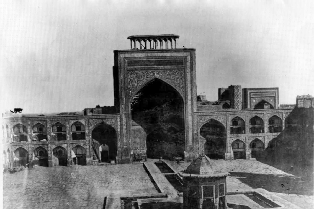 تصویر سیاه و سفید صحن عتیق و نقارهخانه در وسط و سقاخانه اسمال طلا در پایین آن